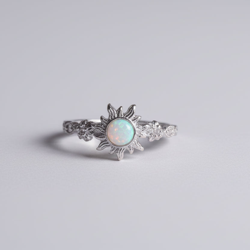 Silver ring with a central opal stone on a light gray background