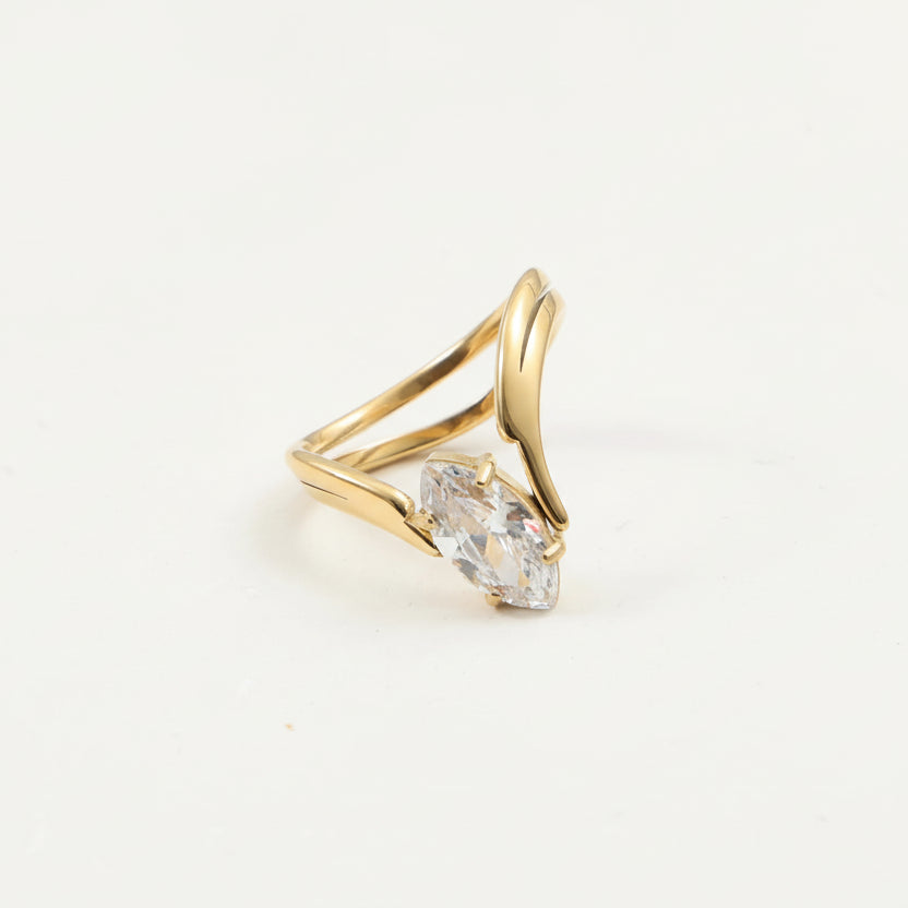 Gold ring with a clear gemstone on a light gray background