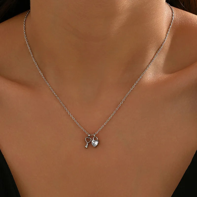Silver necklace with a heart and key pendant on a person's neck