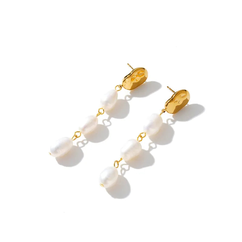 Gold and white pearl earrings on a white background