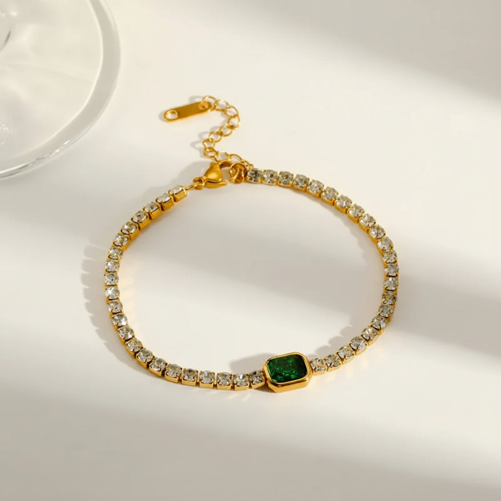 Gold bracelet with green gemstone on a white background