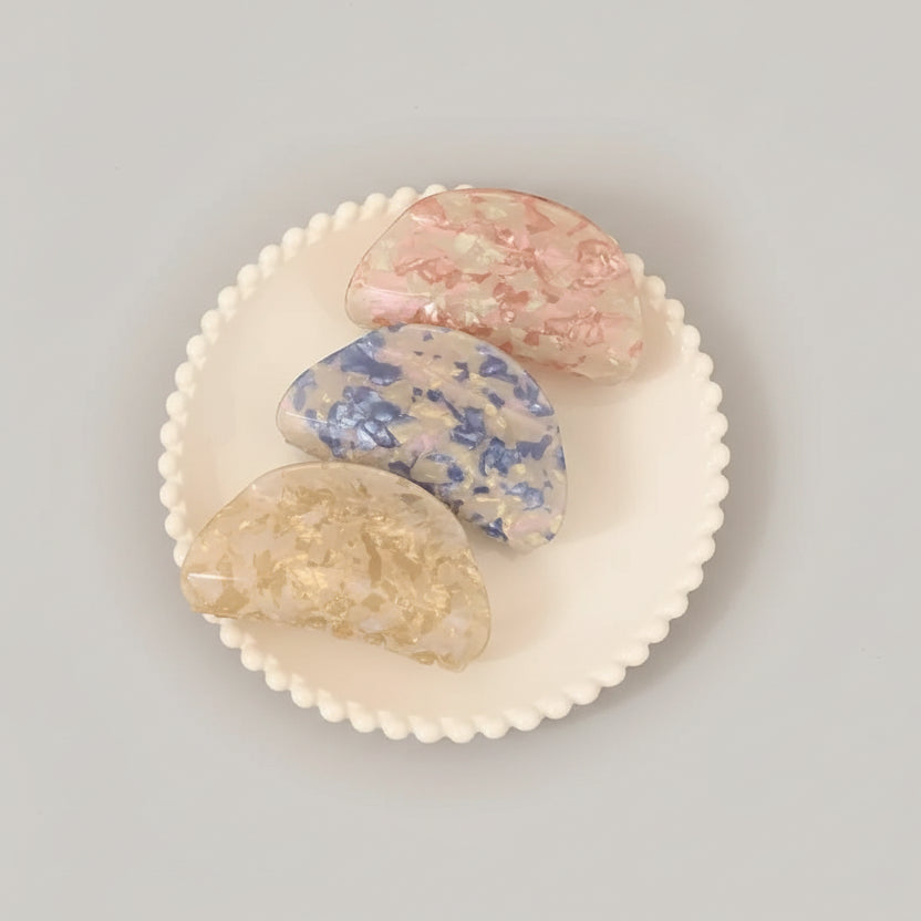 Decorative soap stones on a white plate with a blurred background of a person holding a coffee cup.