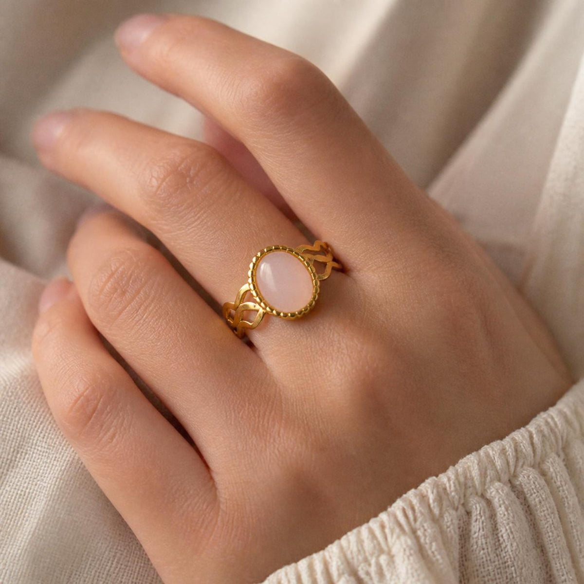 Wiggle Ring worn on finger, showing the pink oval stone with wavy openwork band