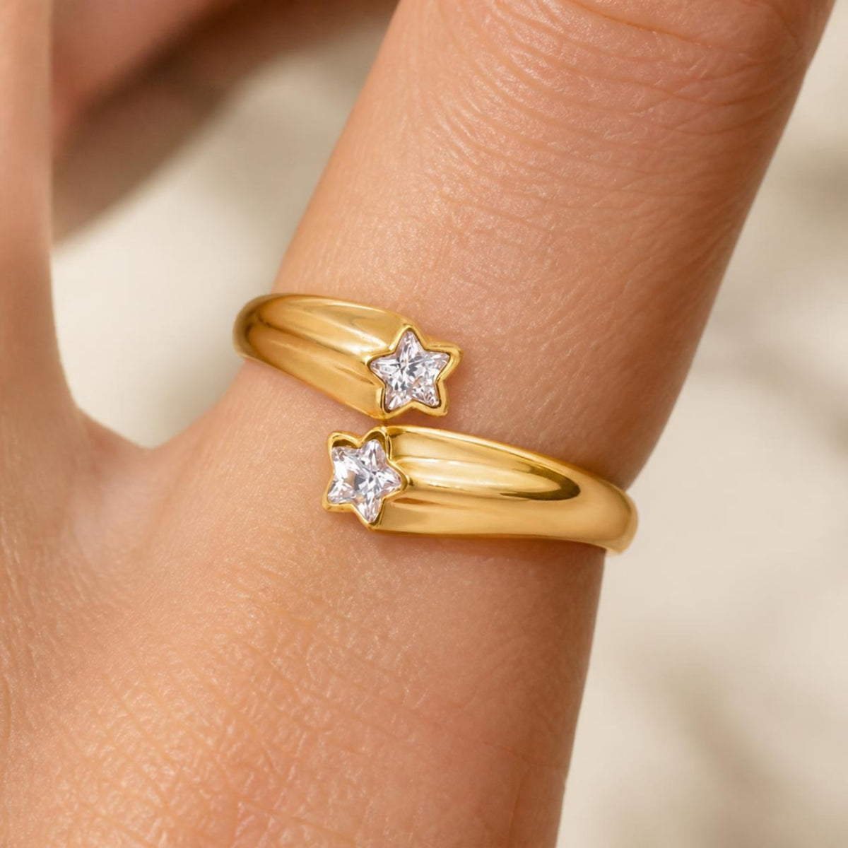 Gold ring with two star-shaped crystal stones worn on a hand