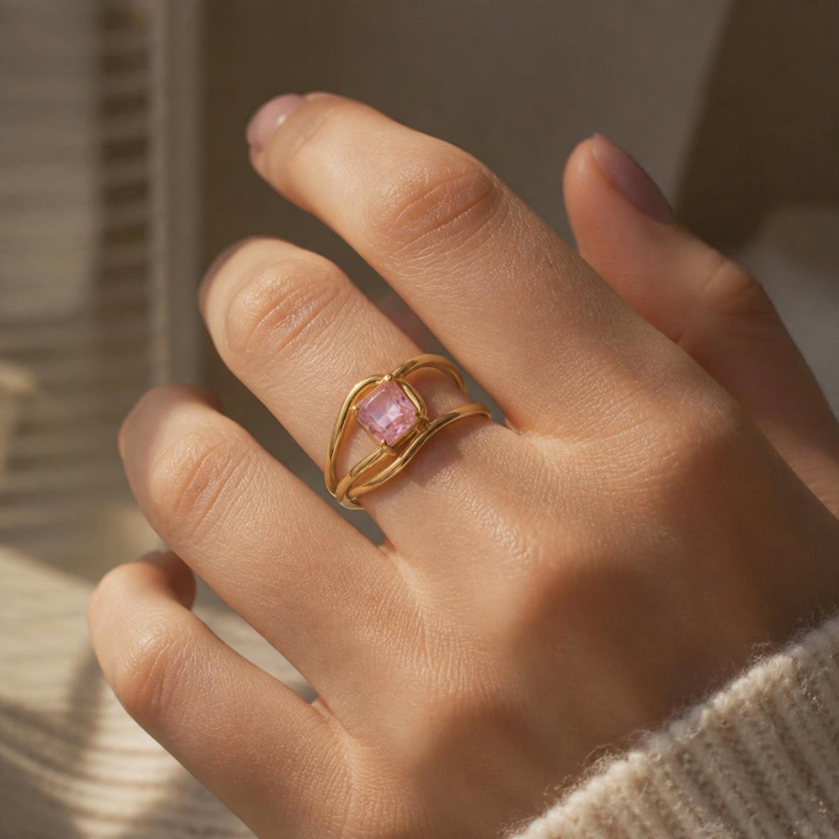 Roselight Ring worn on finger, showing the multi-band cage around the large pink stone