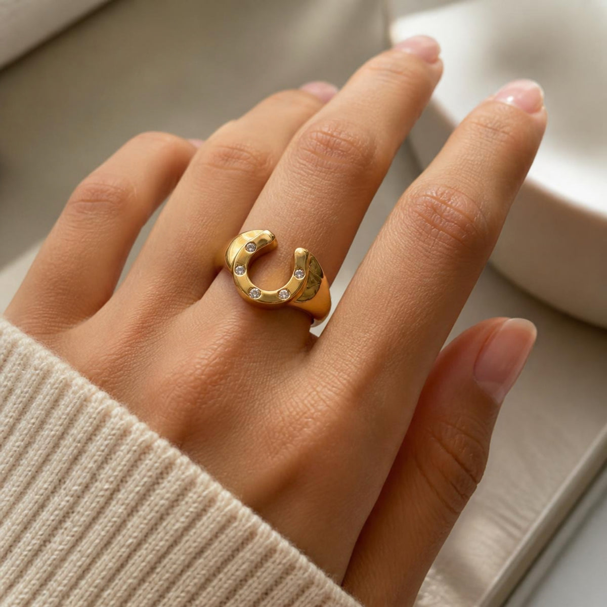 Gold horseshoe ring worn on a hand