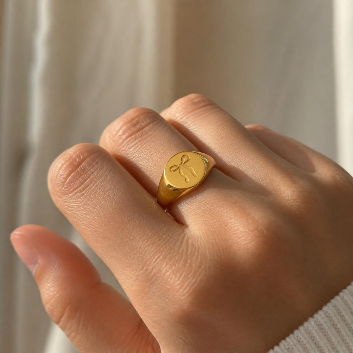 Bow Signet Ring worn on finger, showing the engraved bow detail on the oval signet face