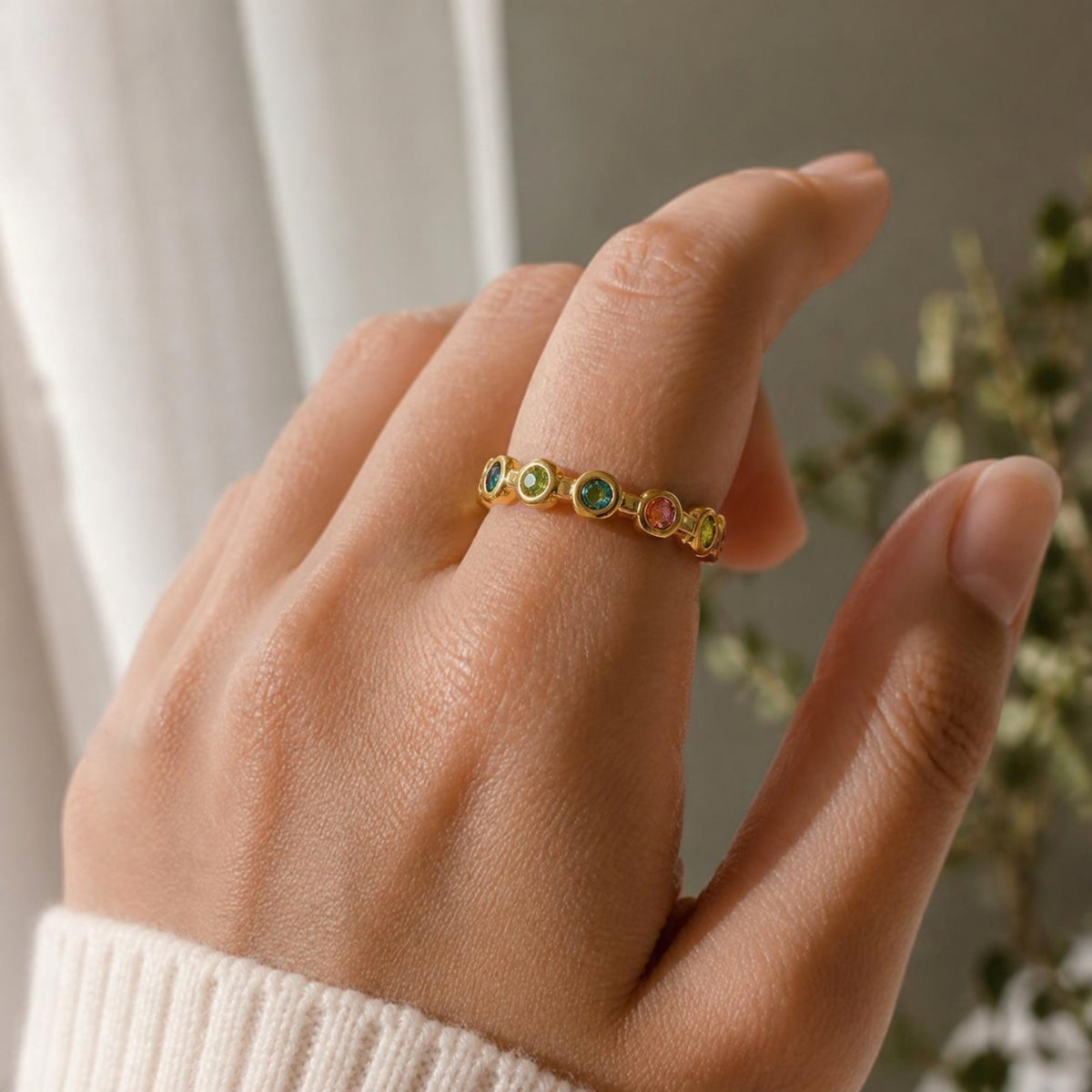 Dream Ring worn on finger, showing the row of multicoloured gemstones