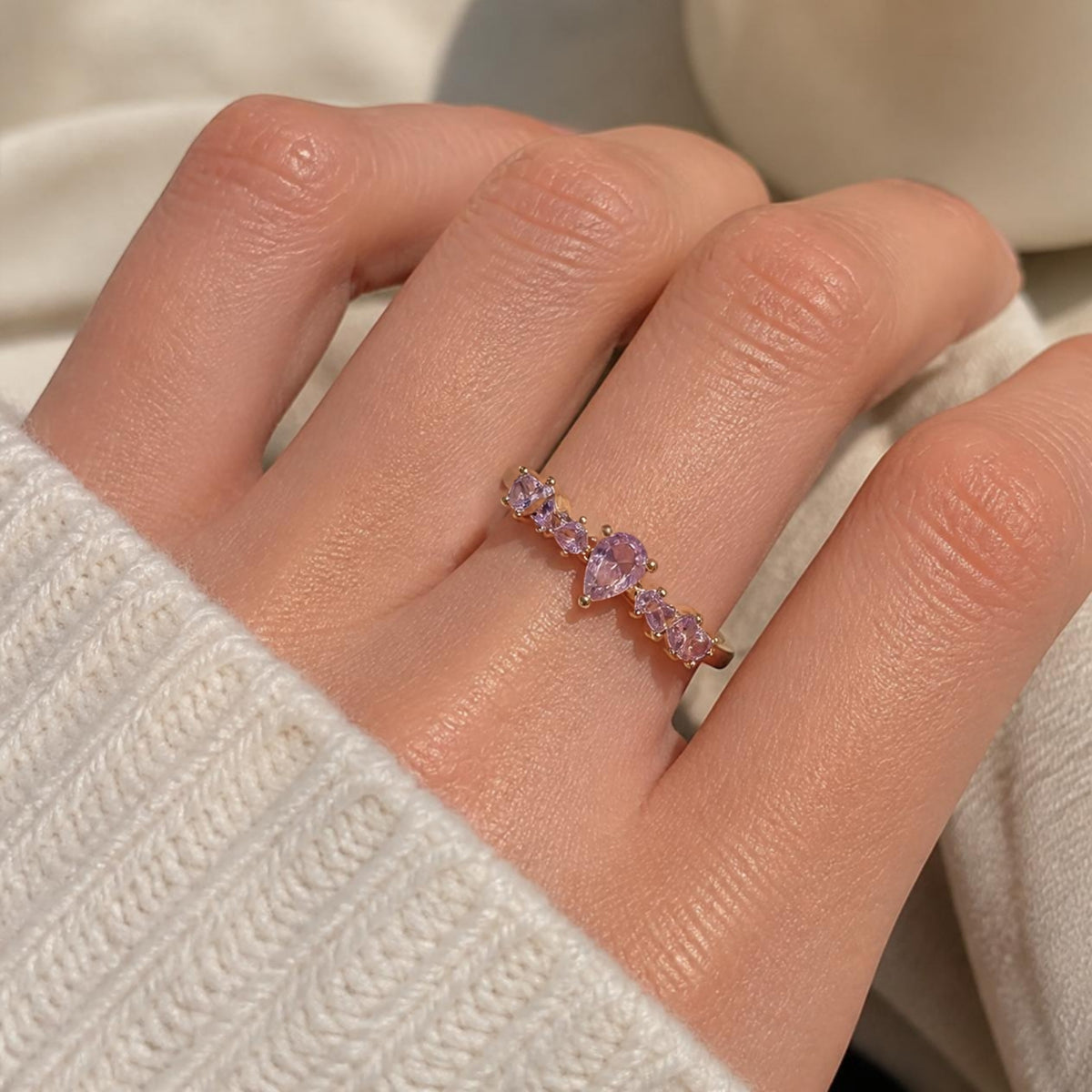 Purple Pear Ring worn on finger, showing the wave of small lilac gemstones along the band