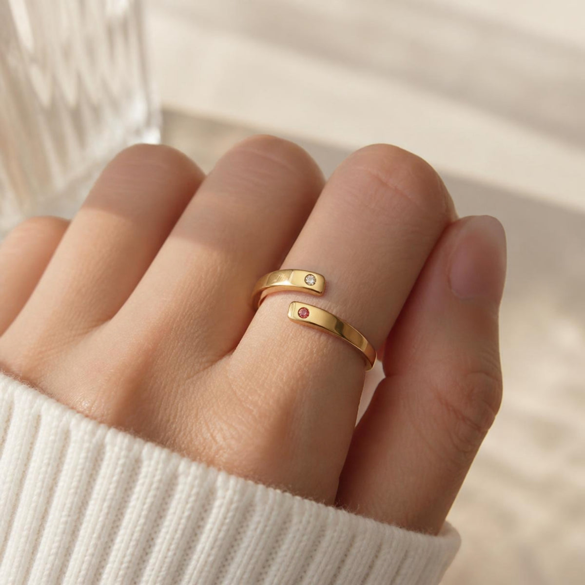 Echo Ring worn on finger, showing the open wraparound band fitted naturally, with clear and pink gemstone tips