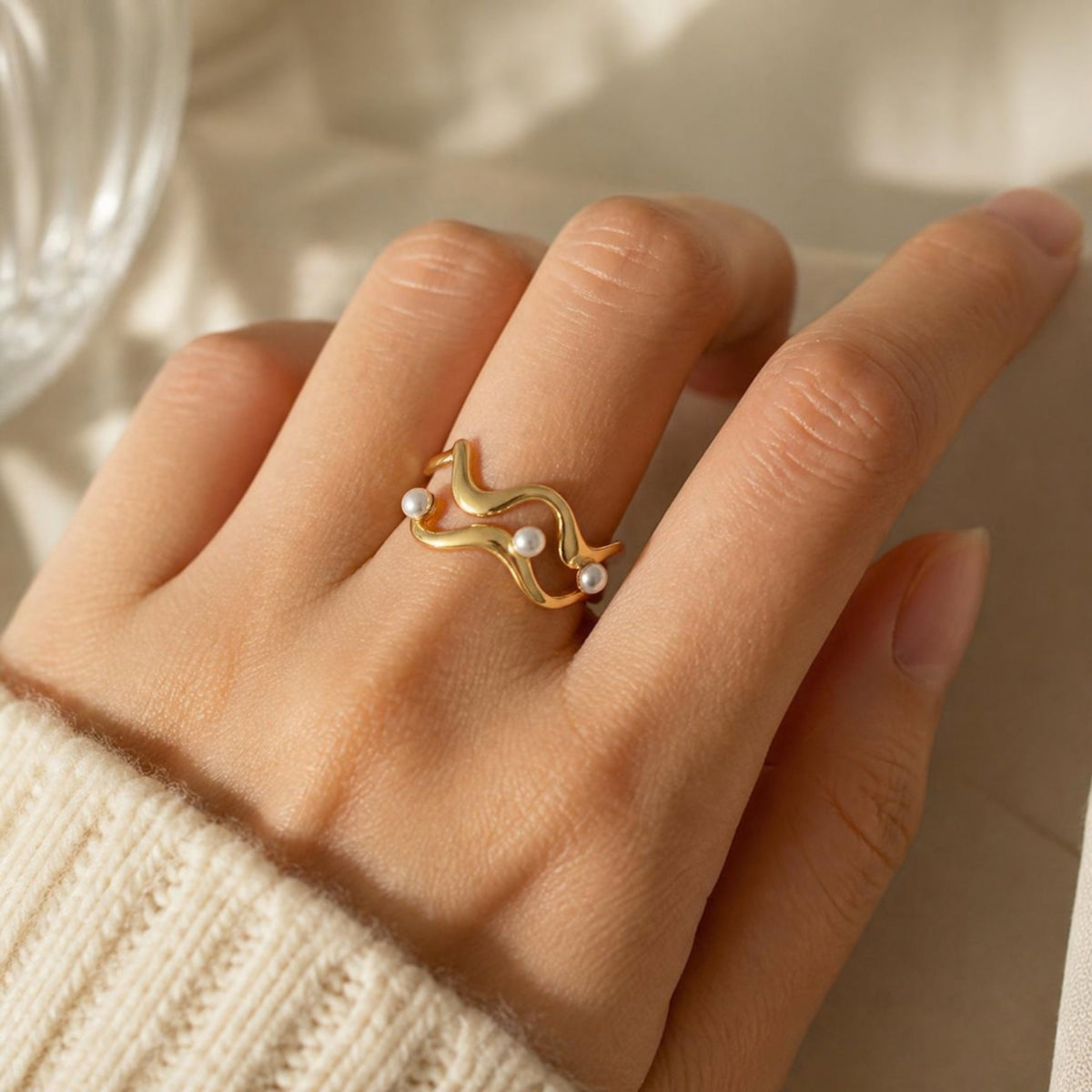 Double Wave Pearl Ring worn on finger, showing the swirling wave design with pearl detailing