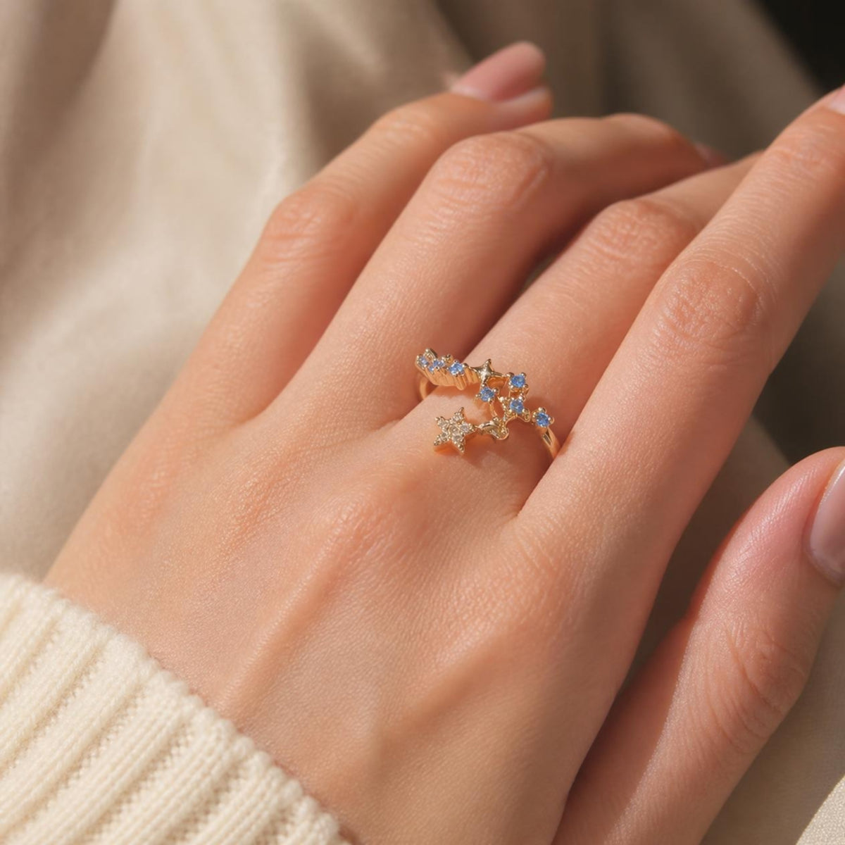 Shooting Star Ring worn on finger, showing the star charms with clear and blue crystals