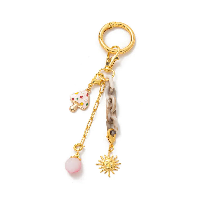 Gold keychain with various charms on a white background