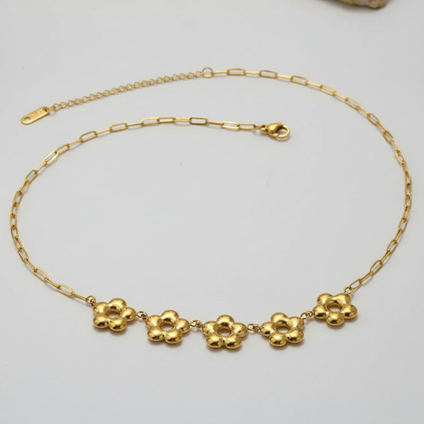Gold necklace with floral pendants on a beige background