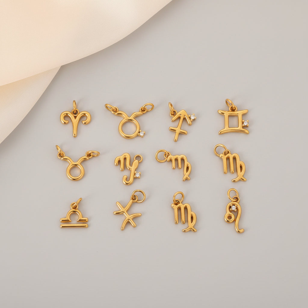 Gold zodiac charm set on a textured beige surface