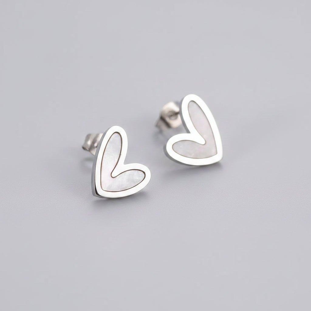Heart-shaped silver earrings on a soft pink background