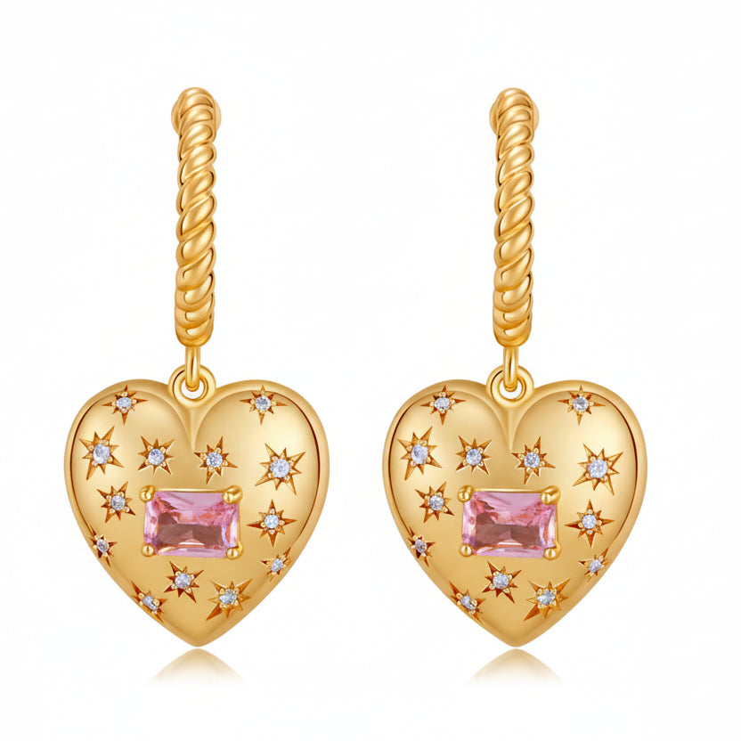 Gold heart-shaped earrings with pink gemstones on a white background