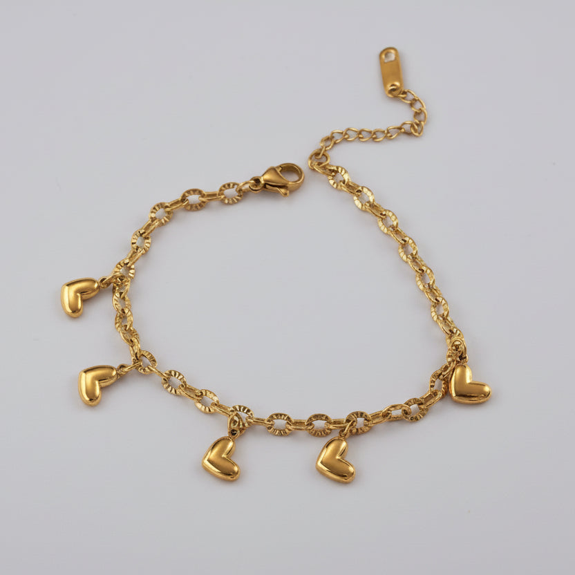 Gold chain bracelet with heart-shaped charms on a white background