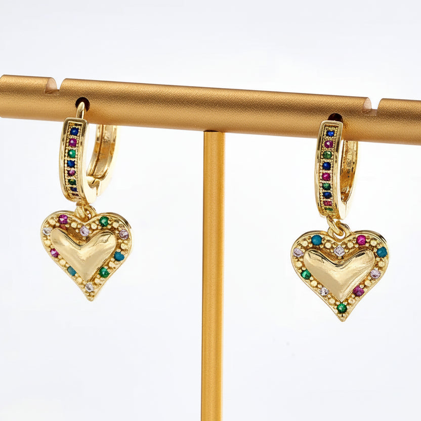 Gold heart-shaped earrings with colorful stones on a gold stand.