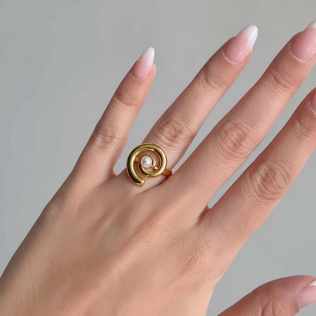 Gold ring with a central gemstone on a hand against a dark background