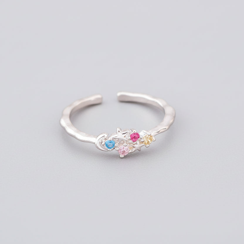 Silver ring with colorful gemstones  and a moon on a surface
