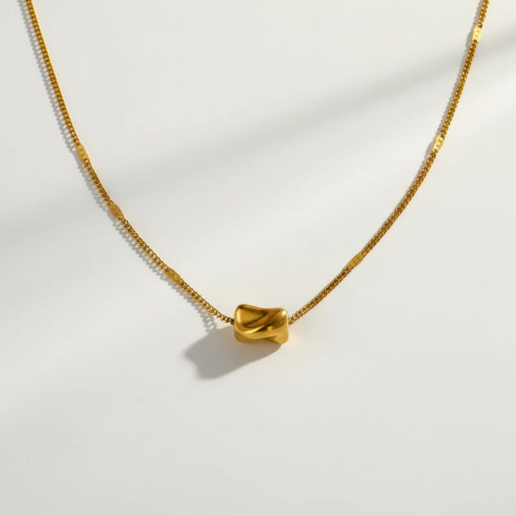 Gold necklace on a textured beige surface