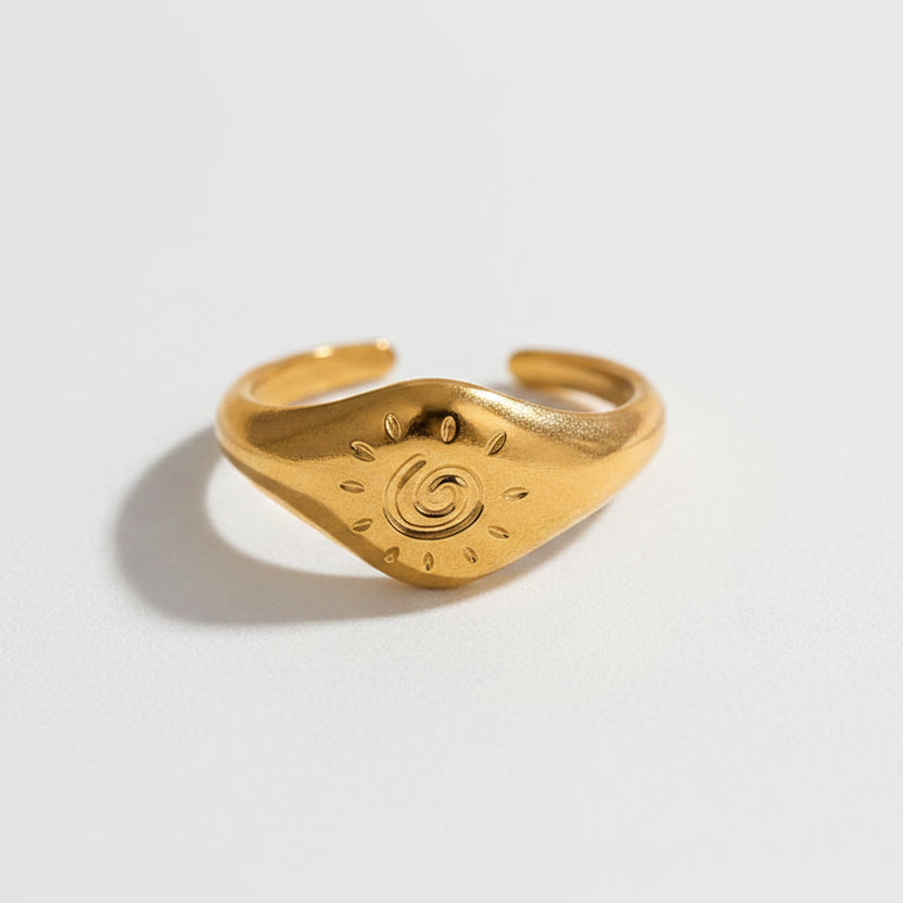Gold ring with engraved design on a white background