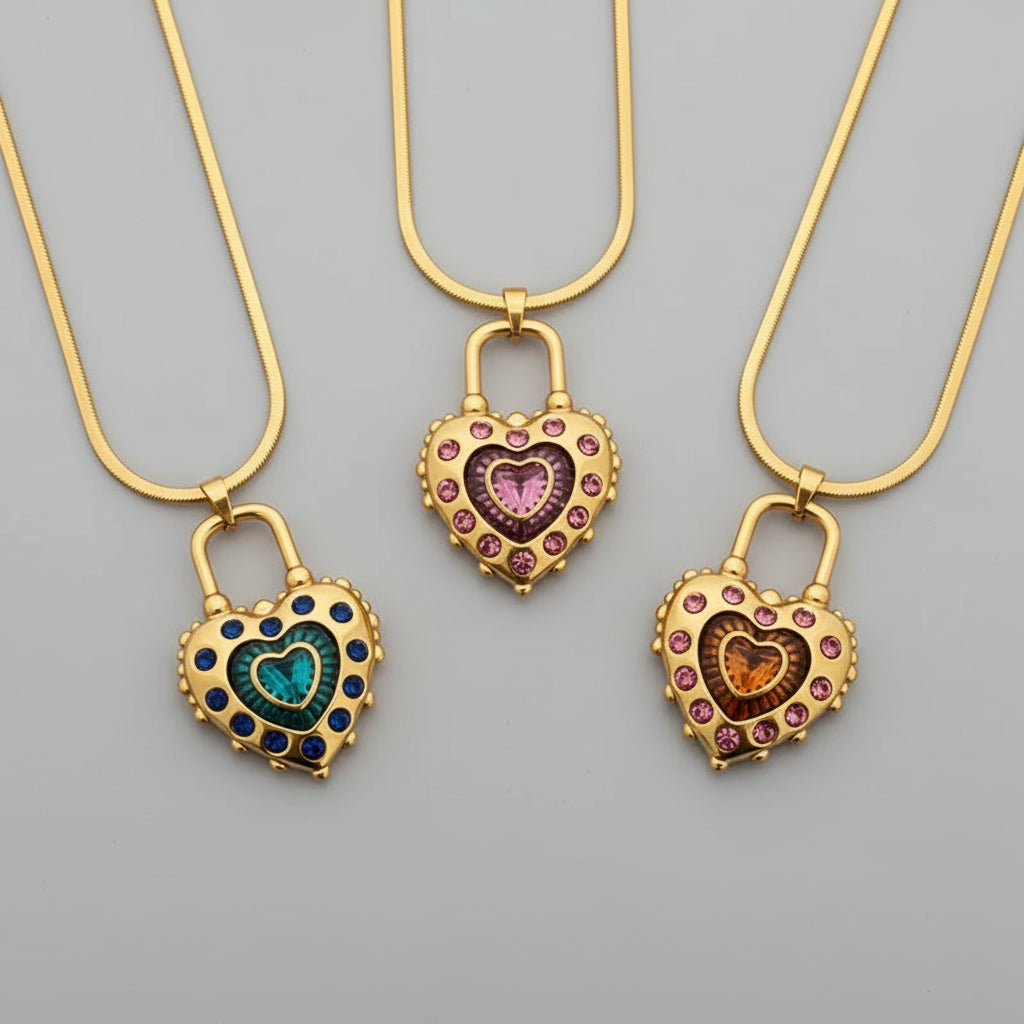 Three gold heart-shaped lock pendants with colorful stones on a light background