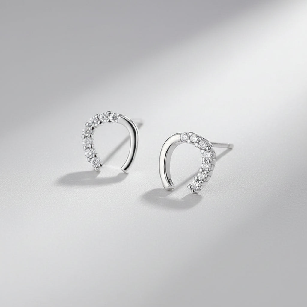 Silver hoop earrings with clear stones on a blue surface