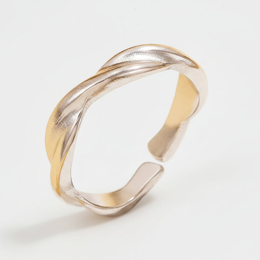 Silver ring with a wavy design on a white stand against a beige background