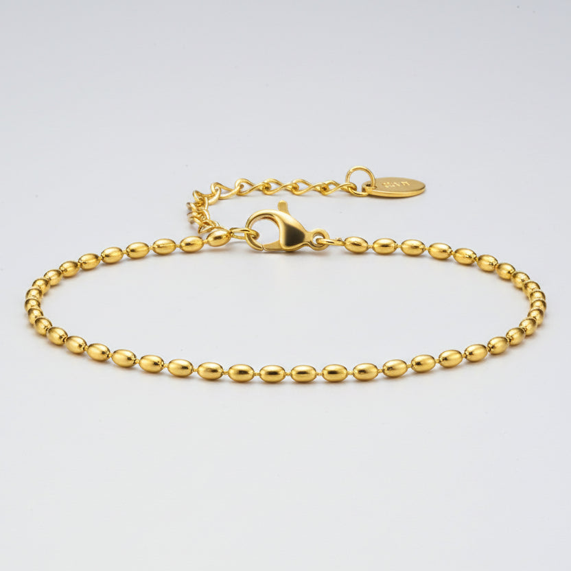 Gold bracelet with bead design on a white background