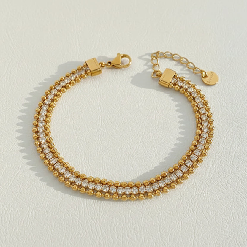 Gold bracelet with clear stones on a light gray background