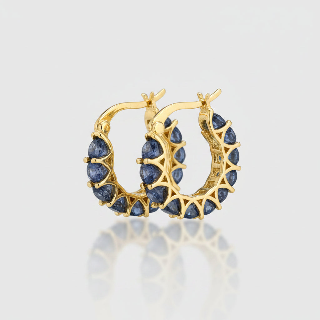 Gold hoop earrings with blue stones on a dark fabric background