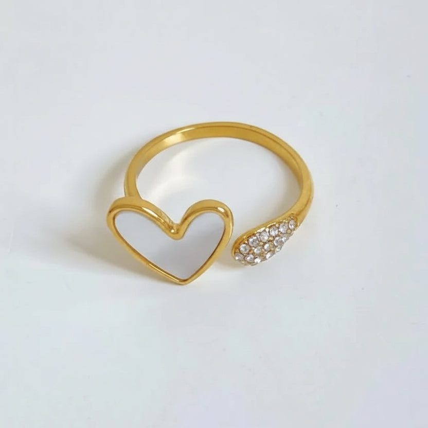 Gold heart-shaped ring with a smaller ring featuring embedded stones on a light gray background.