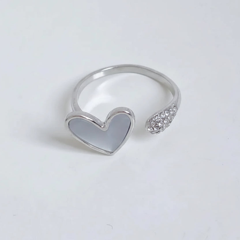 Silver heart-shaped ring with a clear gemstone on a light gray background
