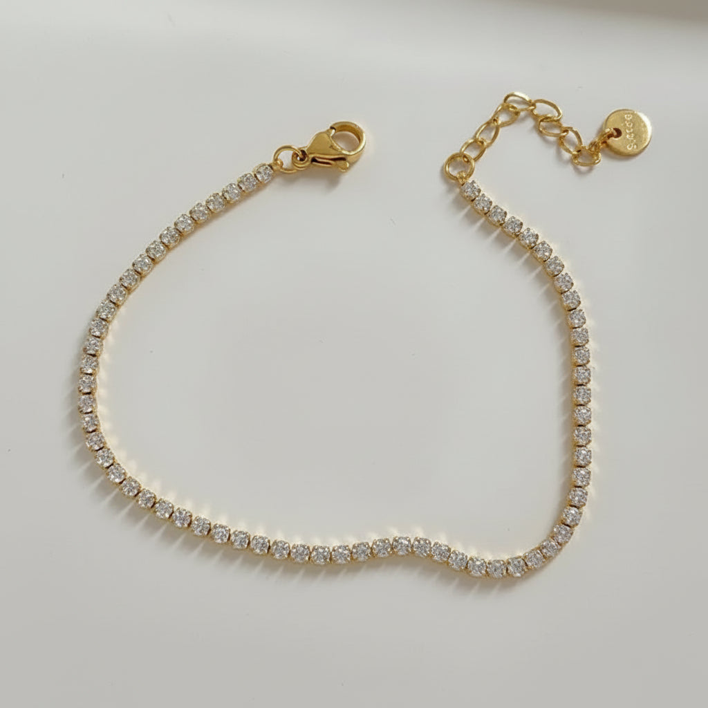 Gold bracelet with clear stones on a light background