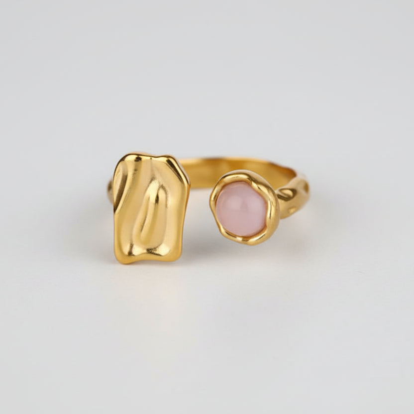 Gold ring with a pink stone s on a white background