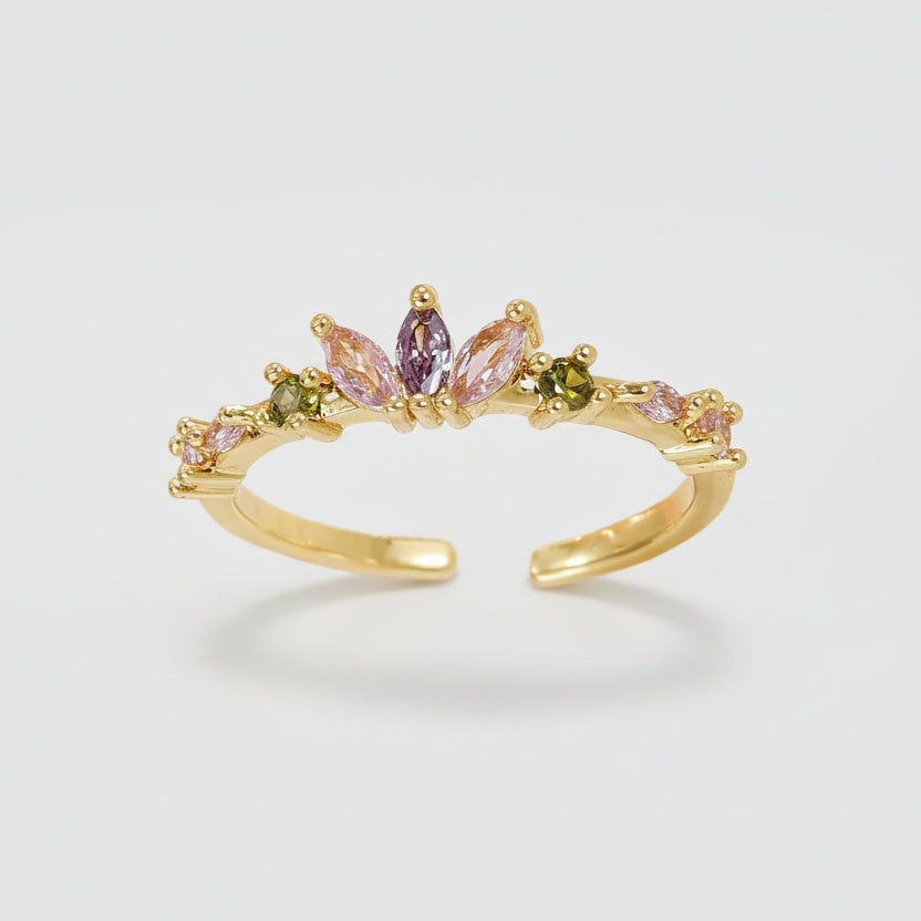 Gold ring with multicolored gemstones on a light gray background