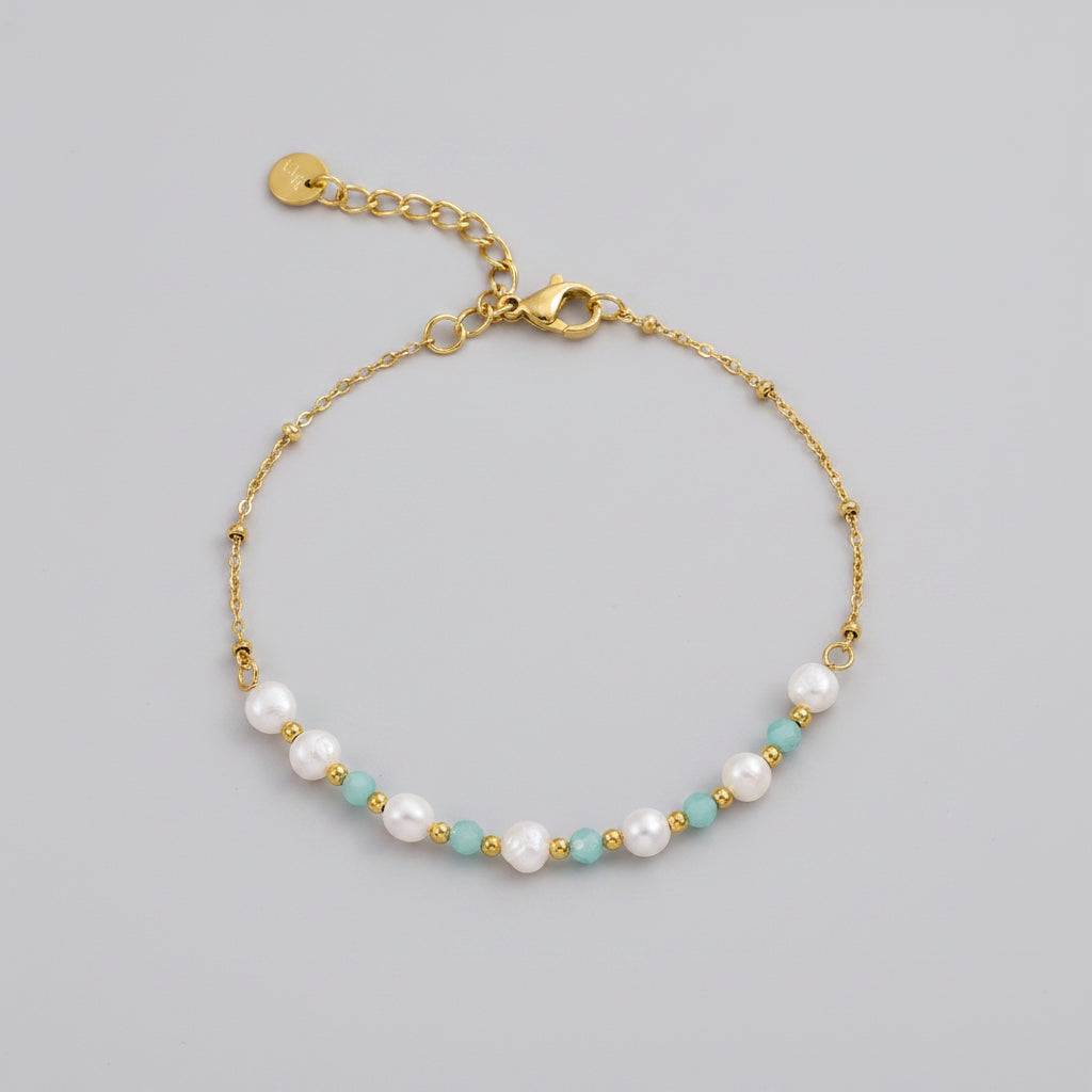 Gold bracelet with pearls and beads on a white background
