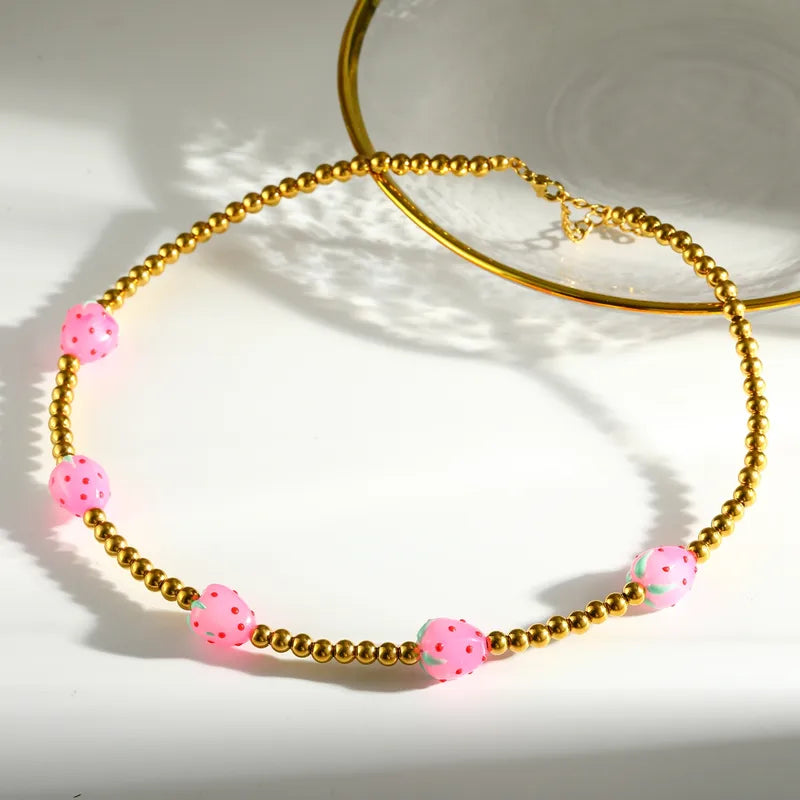 Necklace with pink beads and gold chain on a white background