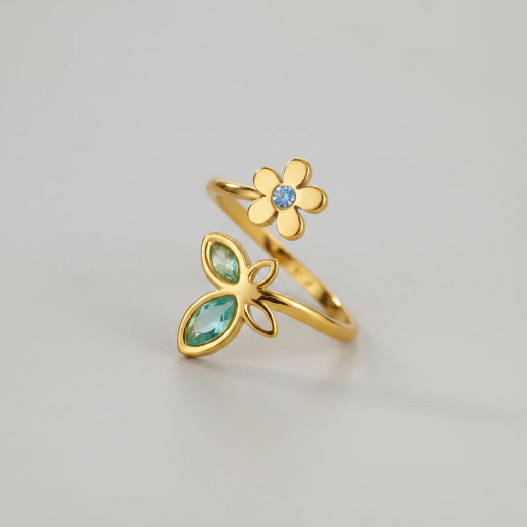 Two gold rings with gemstones on a textured beige surface