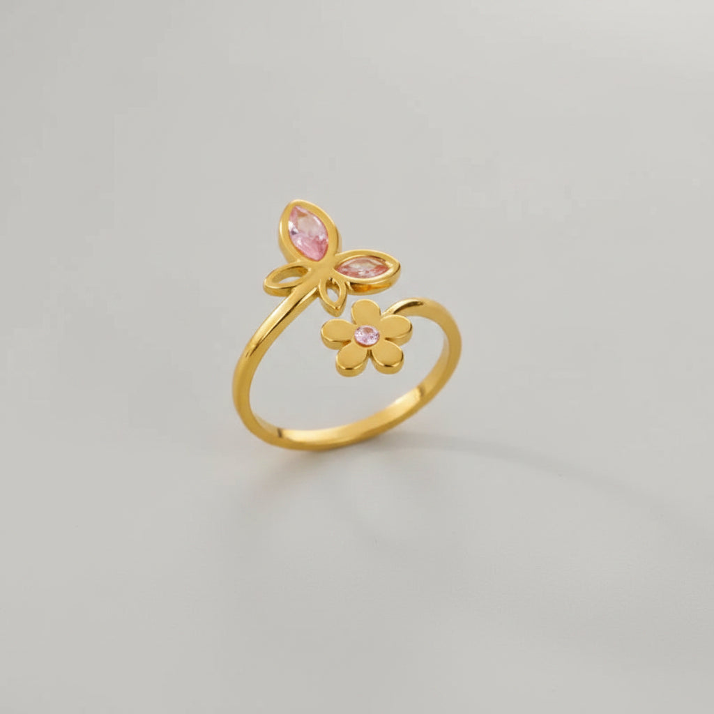 Gold ring with pink gemstones on a beige textured surface