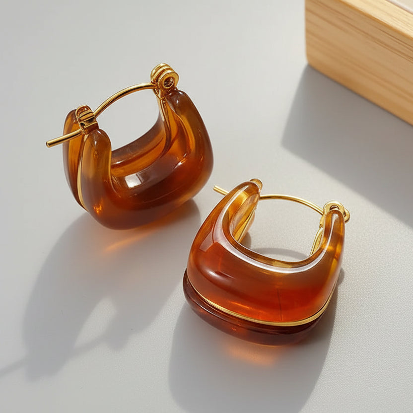 Pair of amber hoop earrings on a beige fabric background