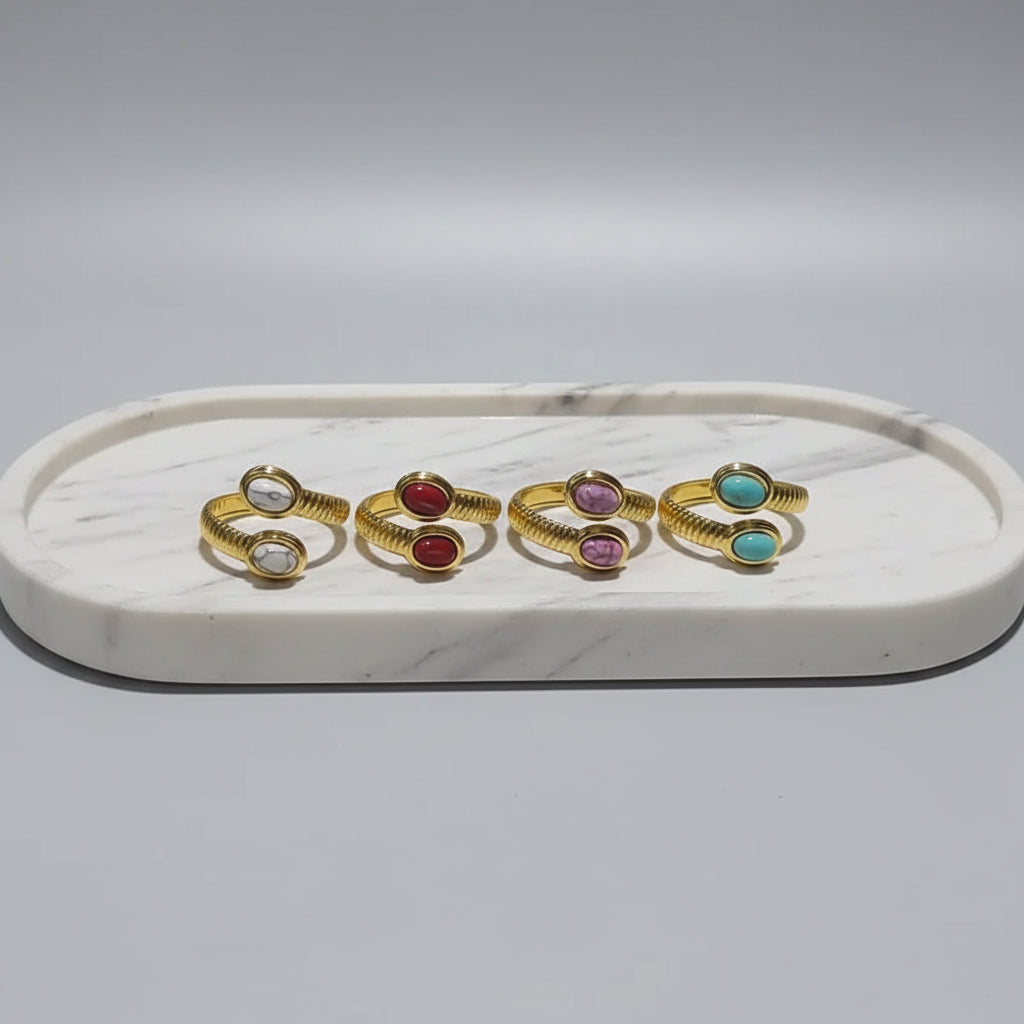 Set of gold rings with colorful stones on a white stand