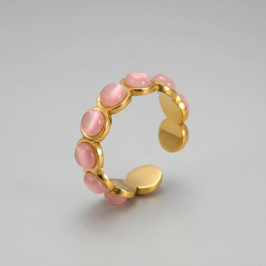 Gold ring with pink stones on a beige background