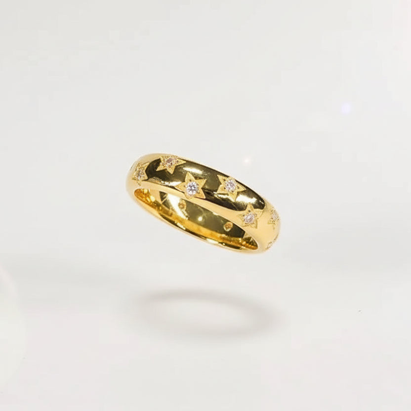 Gold ring with gemstones held between fingers against a blurred jewelry store background