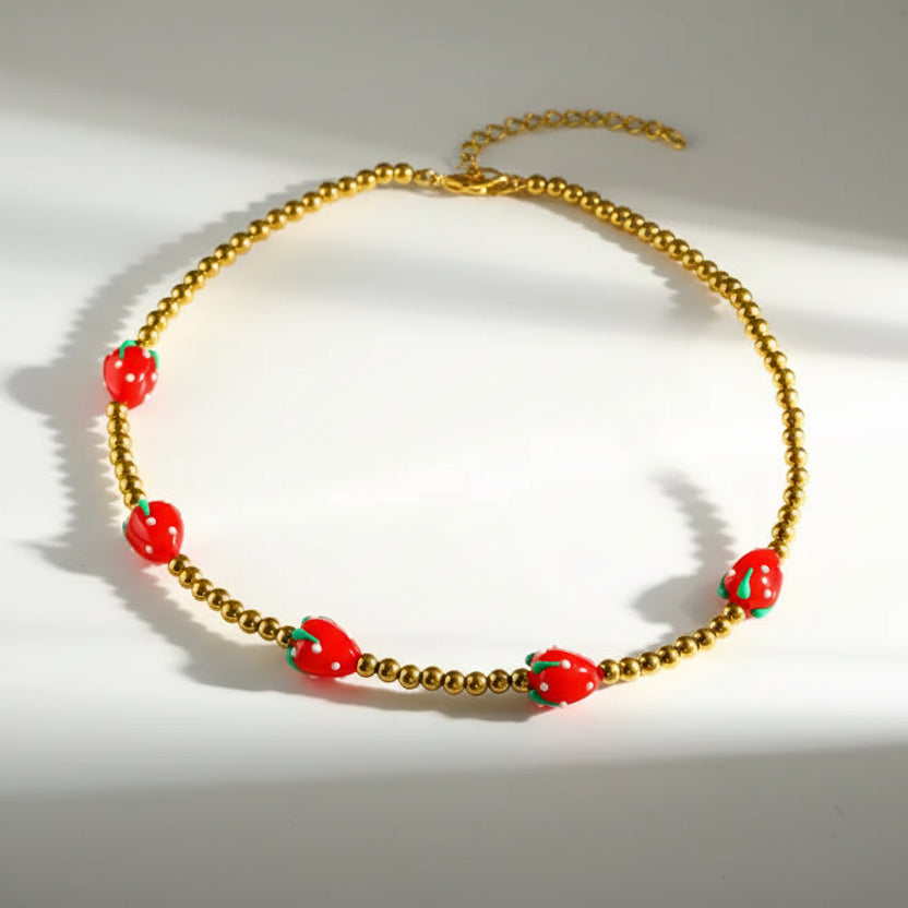Necklace with red strawberry-shaped beads on a white background