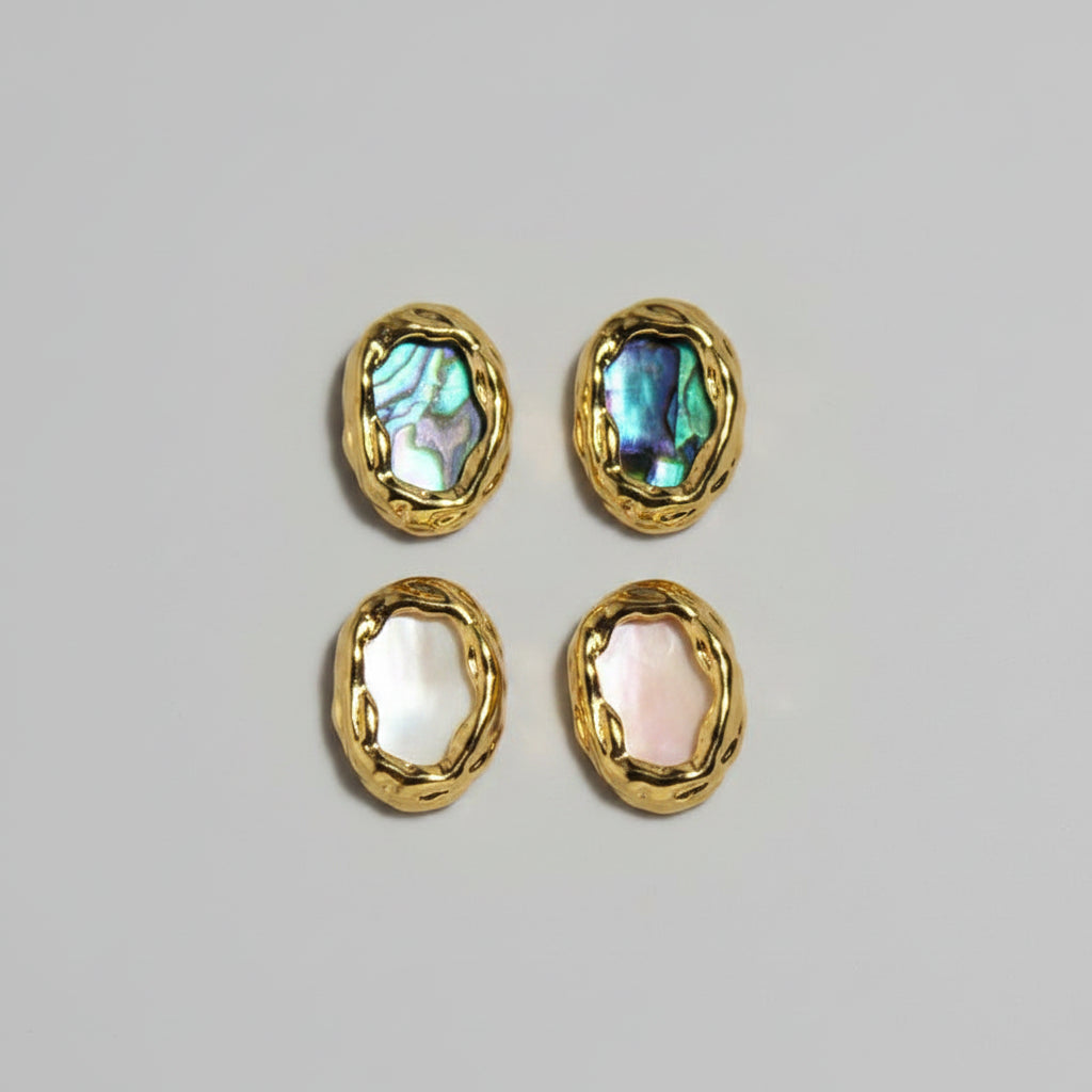 Gold-framed earrings with colorful gemstones on a white fabric background