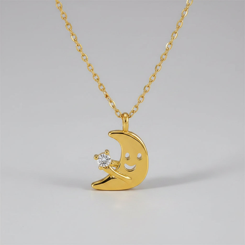 Gold necklace with a crescent moon and star pendant on a beige surface.