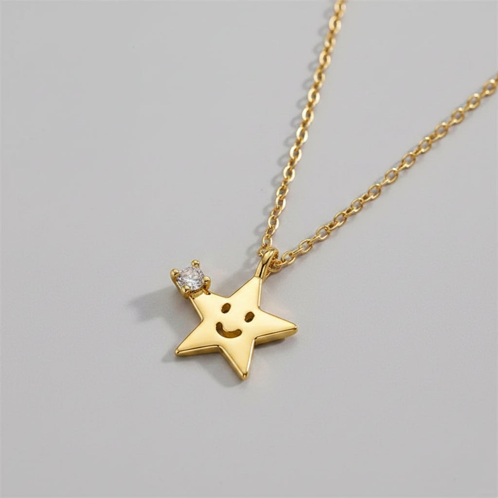 Gold star necklace with a smiley face design on a beige surface
